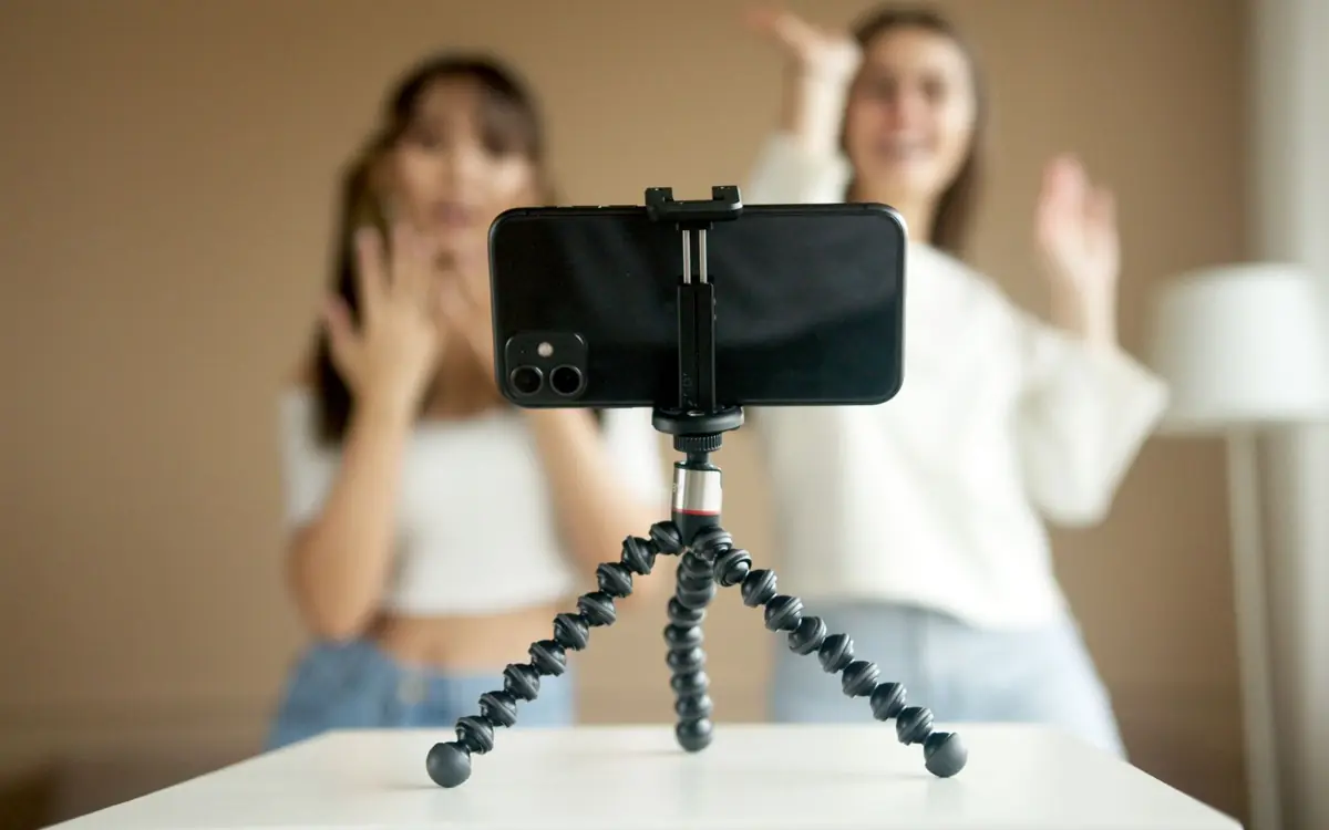 Two women recording an Instagram Reel on a smartphone fixed to a tripod at home