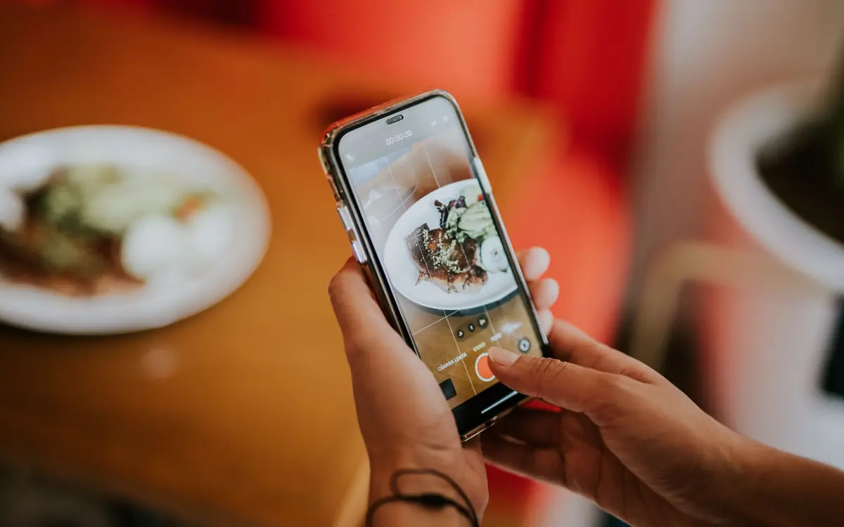 Phone filming food at a cafe table, a simple reel idea for restaurants and small food businesses